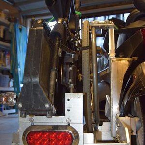 The rack is attached to the frame of the Spyder not the swing arm. It attaches just behind the passenger's left foot and just below the left turn sign