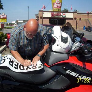 Tom signing the banner by accident. Some lookers knew someone who had a spyder so they went off to get him. When he arrived he mentioned his spyder wa