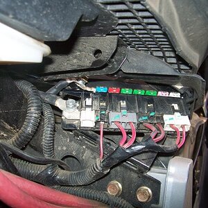 Here is the main fuse block under the seat seen from inside the guard. The cover is open to expose the fuses. The nut on the left is live.