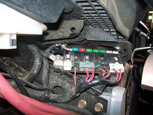 Here is the main fuse block under the seat seen from inside the guard. The cover is open to expose the fuses. The nut on the left is live.