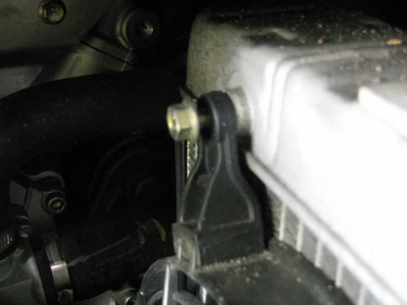 Loosen top left fan mounting bolt