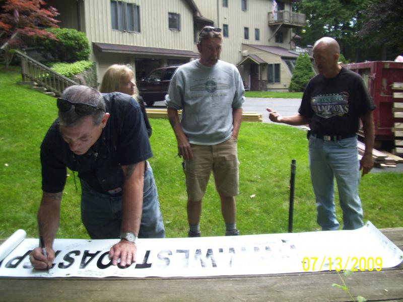 Mike signing the banner, Kim behind, then Lou and Dudley.